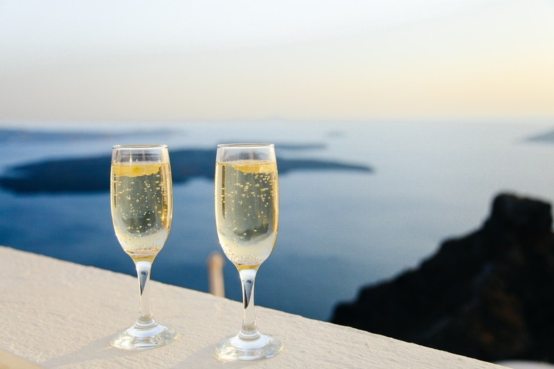 Glasses of sparkling wine on a ledge overlooking the ocean.